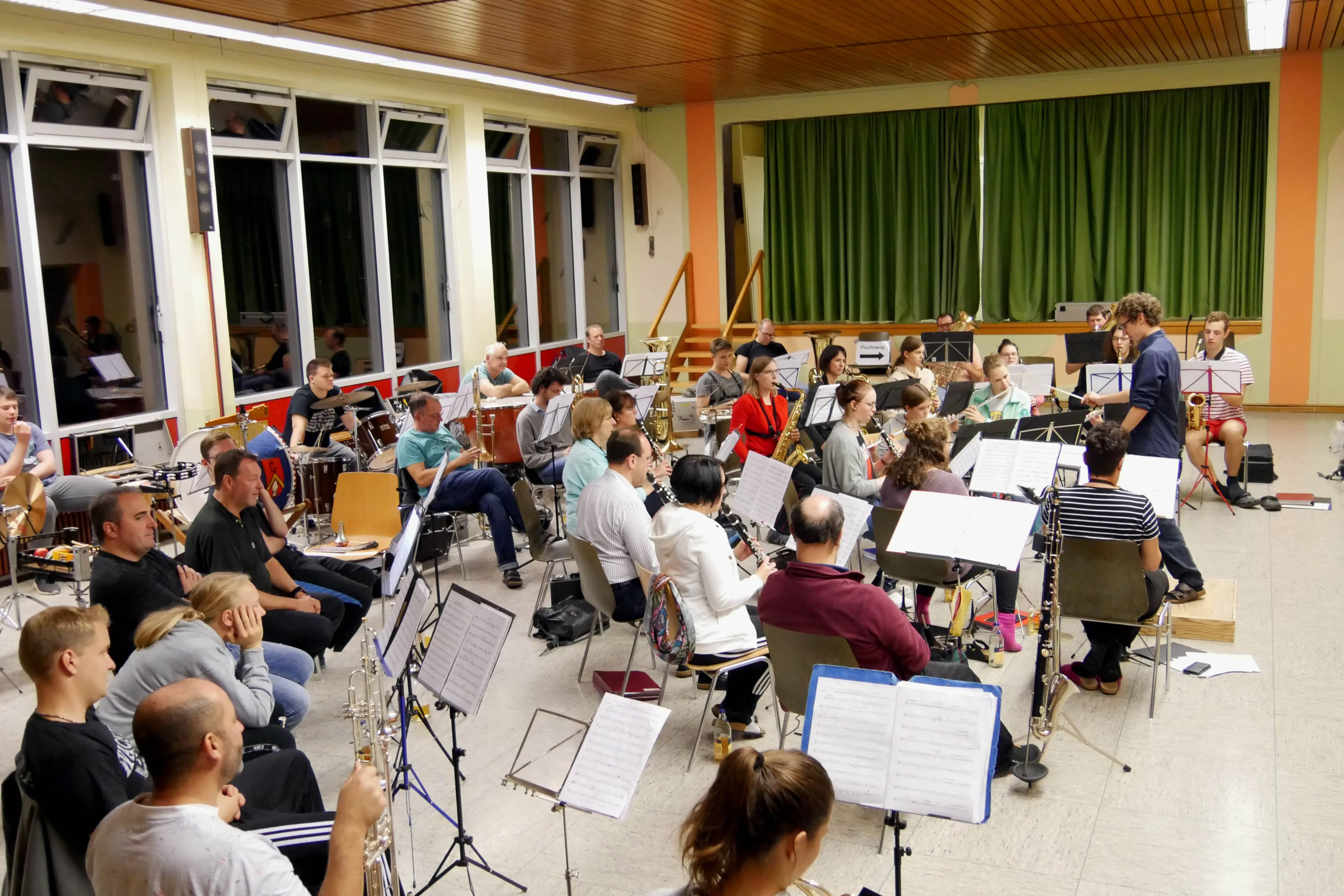 Das Orchester probt beim Probewochenende in einer großen Halle mit Noten und Instrumenten