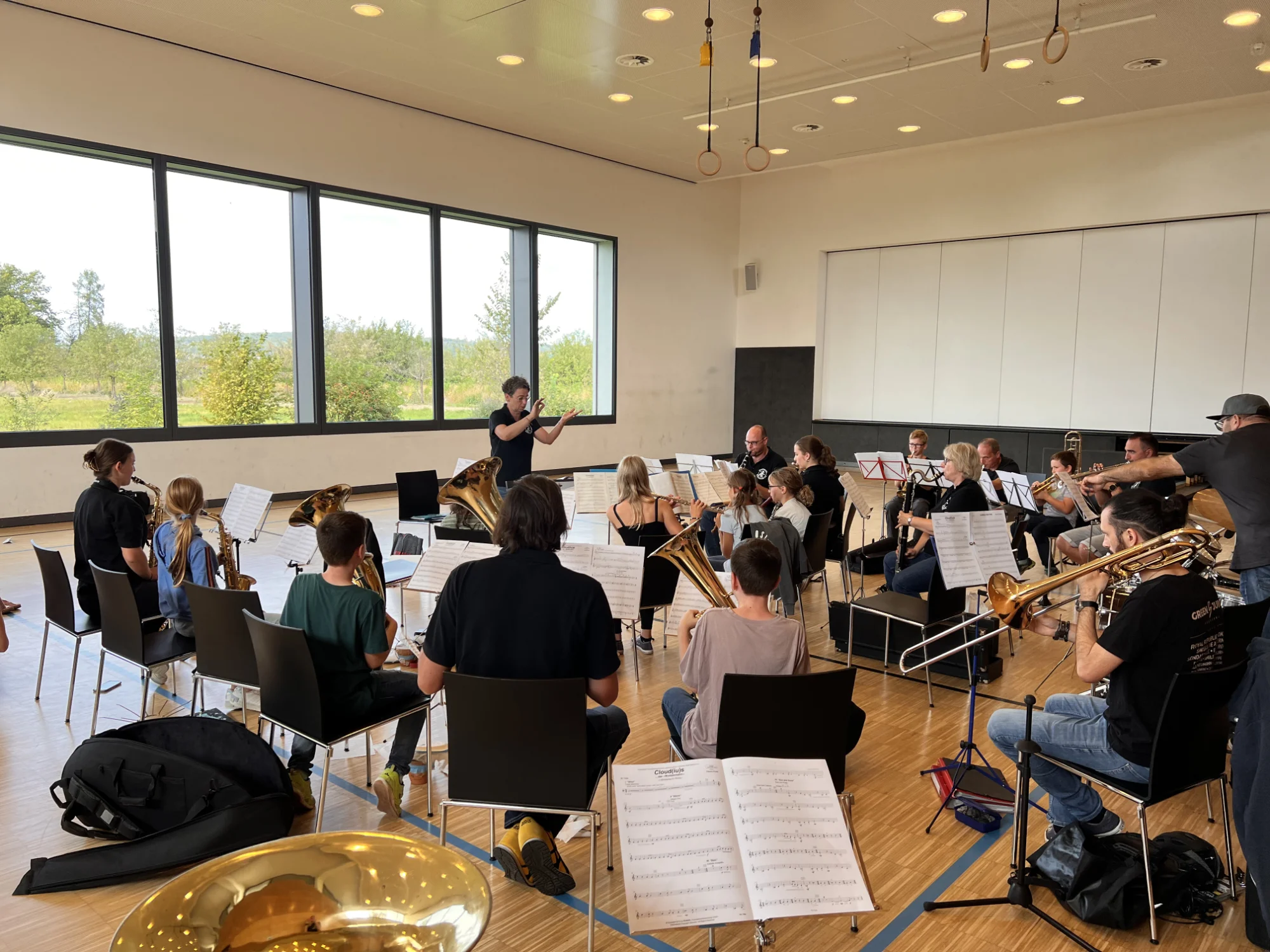 Orchesterprobe beim 1. Jugendtag 2024 in einem hellen Saal mit großen Fenstern, Noten und Blasinstrumenten