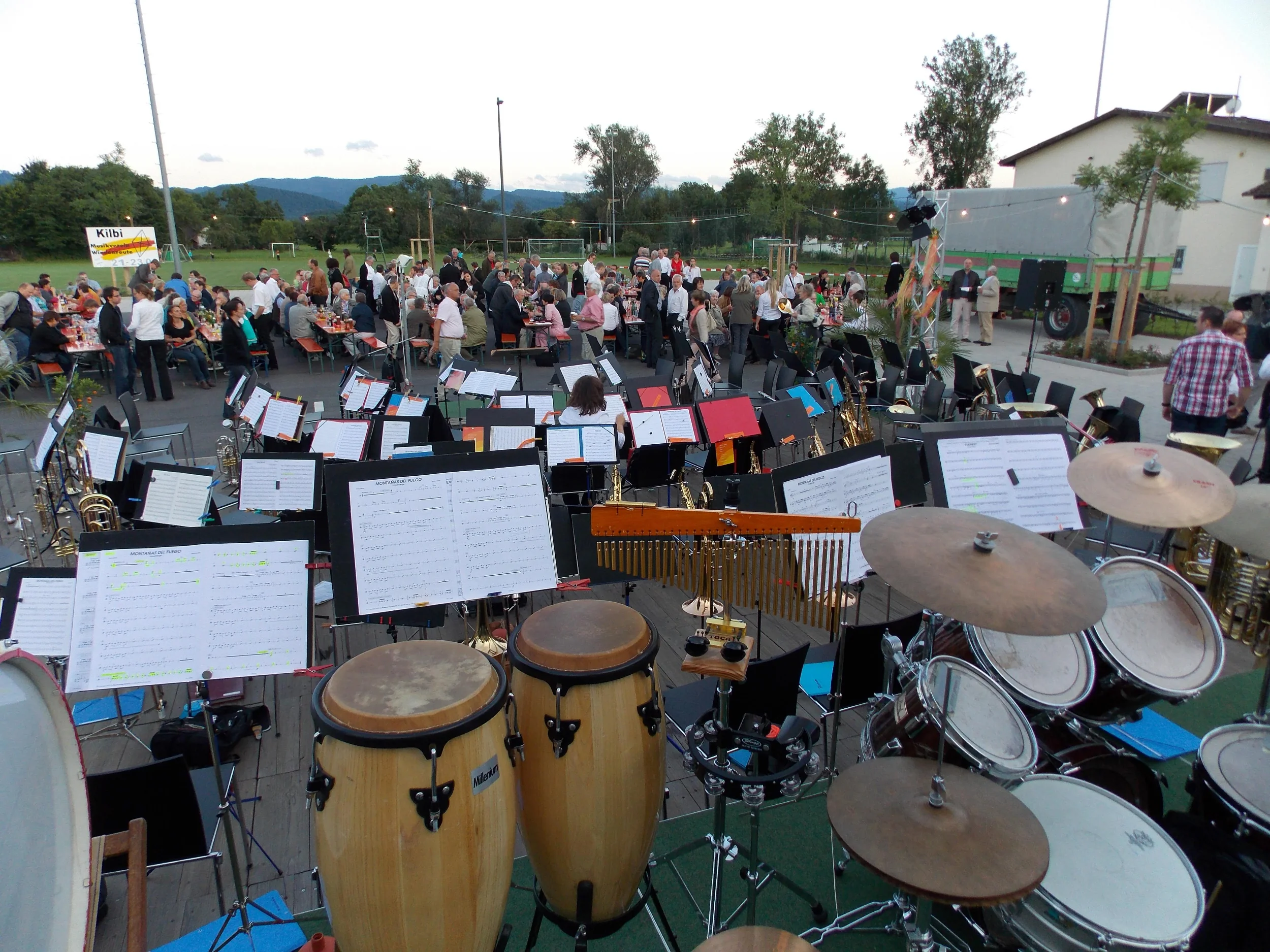 Das Projektorchester spielt im Freien, im Vordergrund Congas, Schlagzeug und Notenständer, dahinter das Publikum