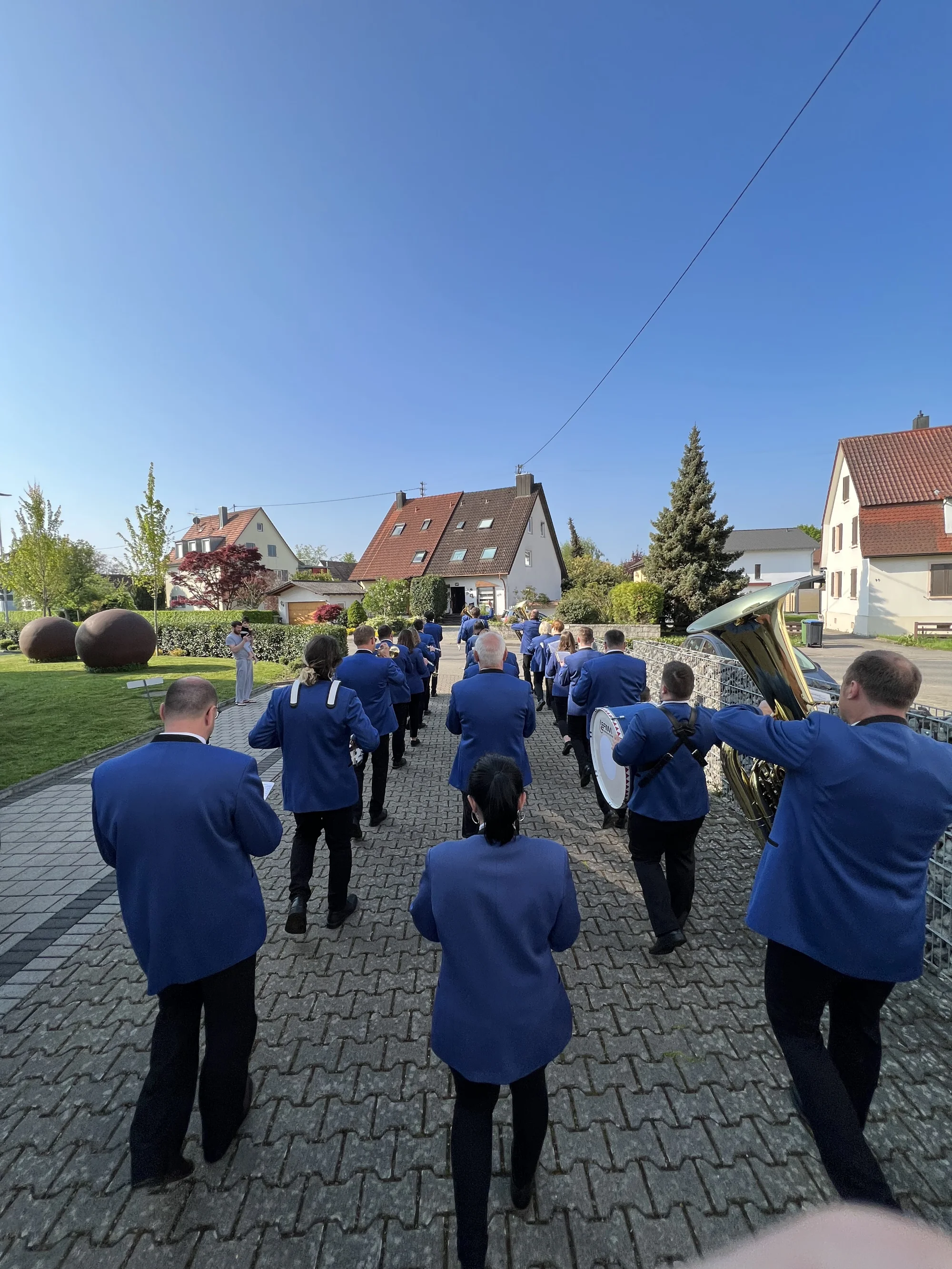 Die Musikkapelle in blauen Jacken marschiert am 1. Mai durch eine Dorfstraße