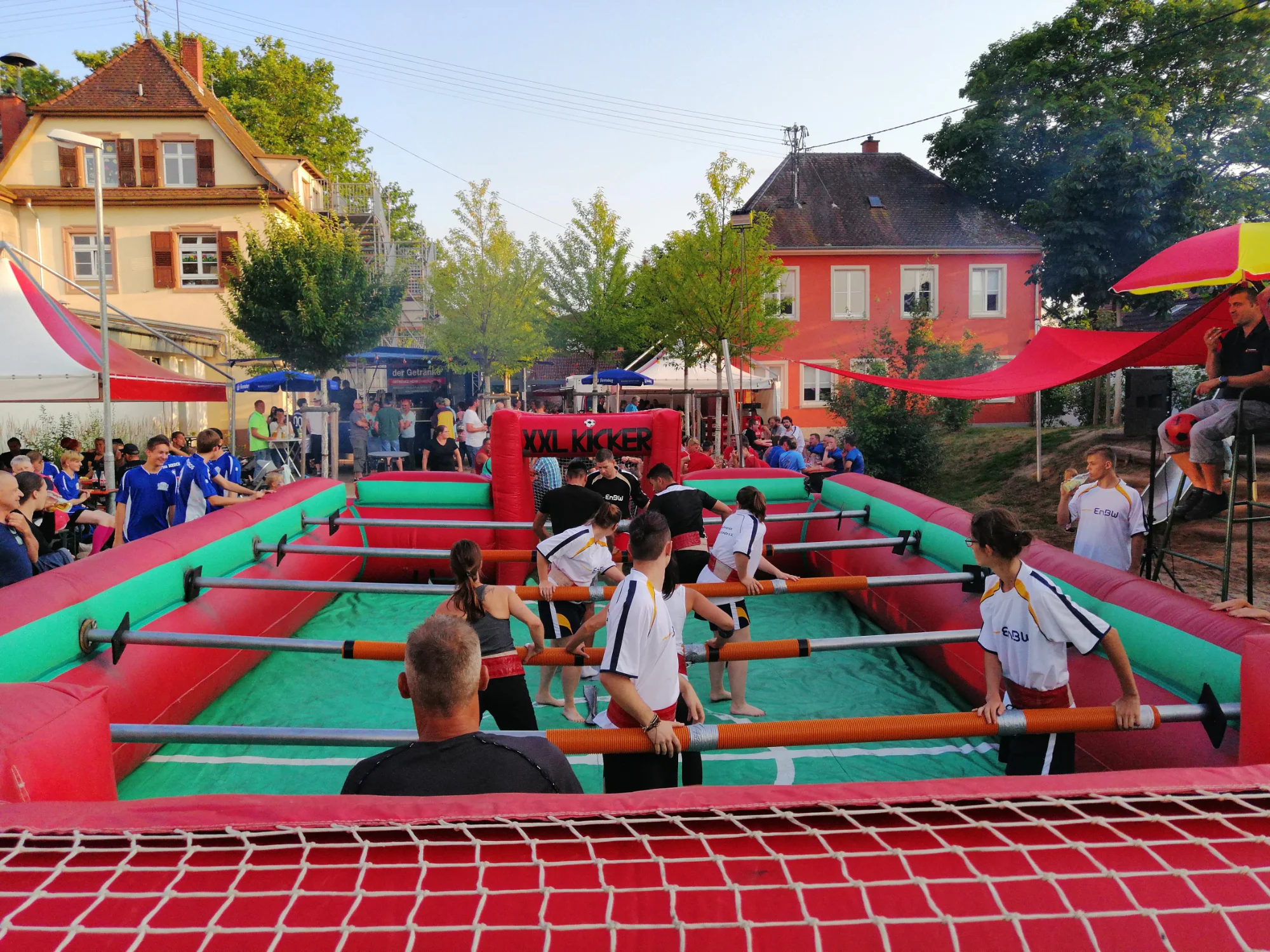 Menschenkicker XXL: Spielerinnen und Spieler an den Stangen eines riesigen aufblasbaren Kickertischs