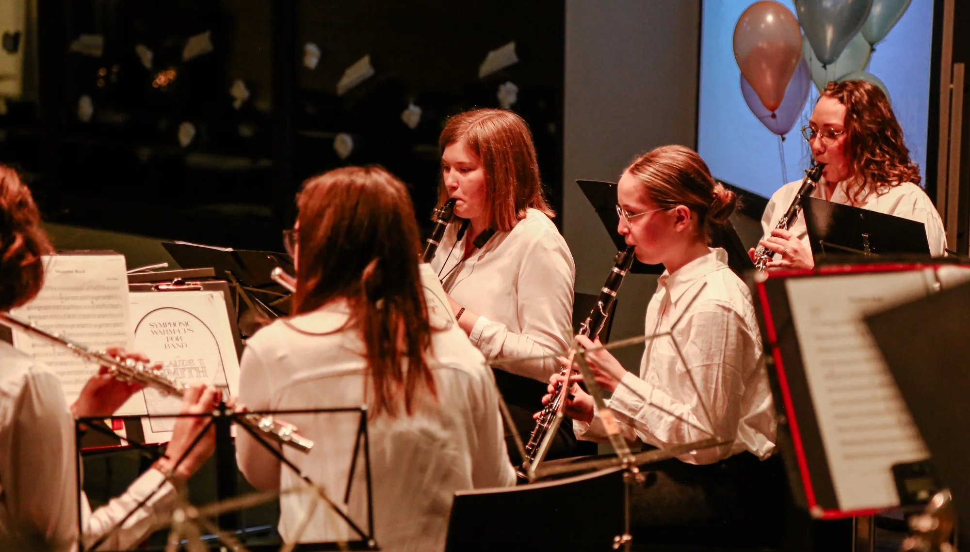 Jugendliche Klarinettistinnen und Flötistinnen in weißen Blusen bei einem Konzert des Jugendorchesters